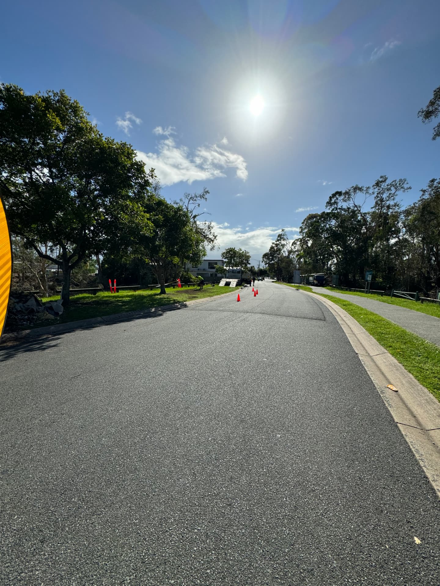 Traffic-controlled street with cones and signage during storm debris clearance works