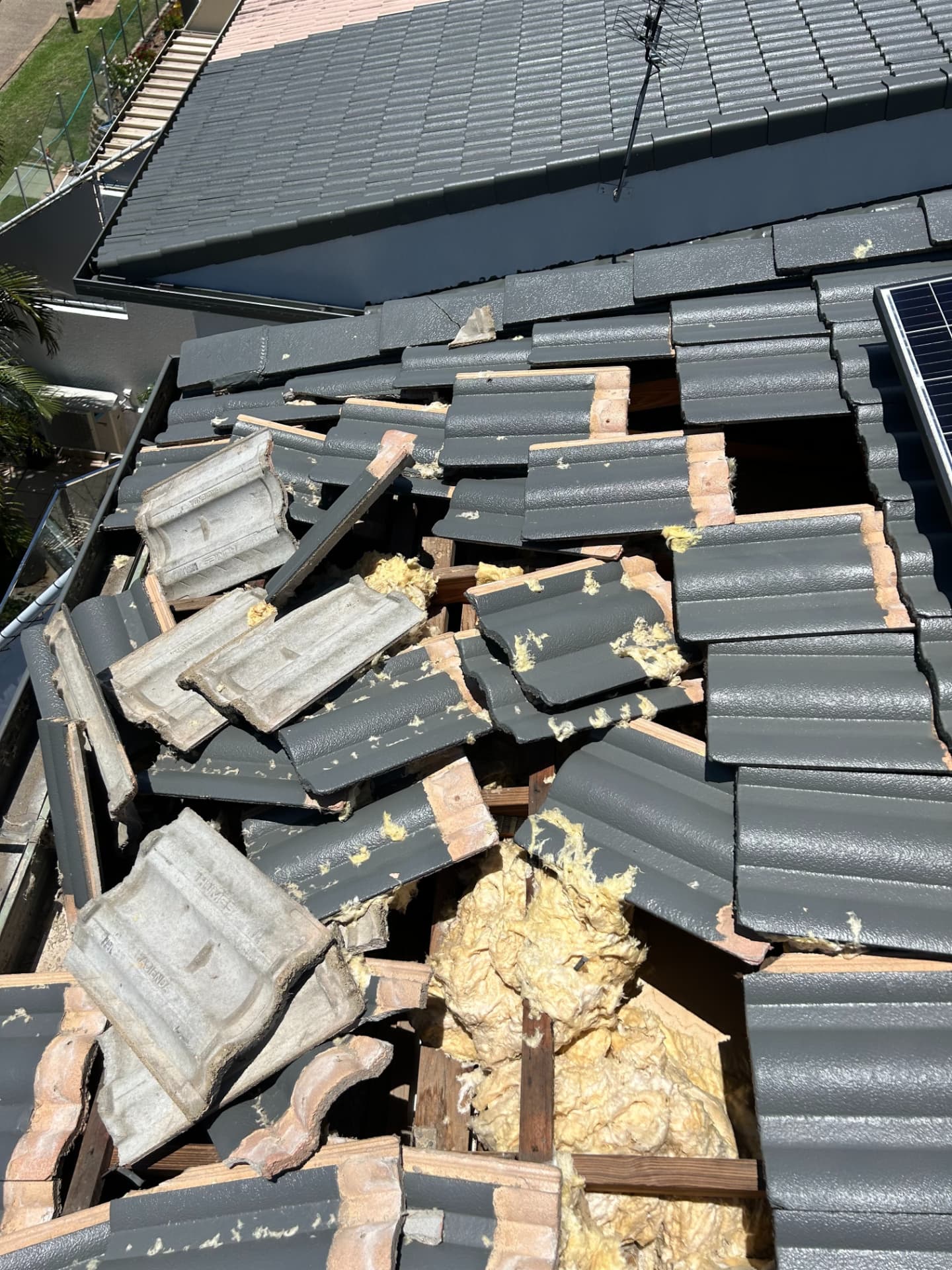 Broken and displaced roof tiles with exposed battens and insulation after tornado damage