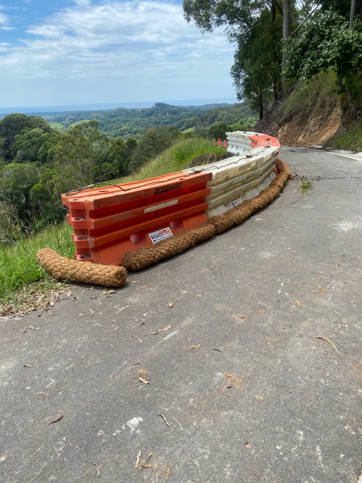 Line of temporary barriers and erosion control logs protecting a slipped roadway edge
