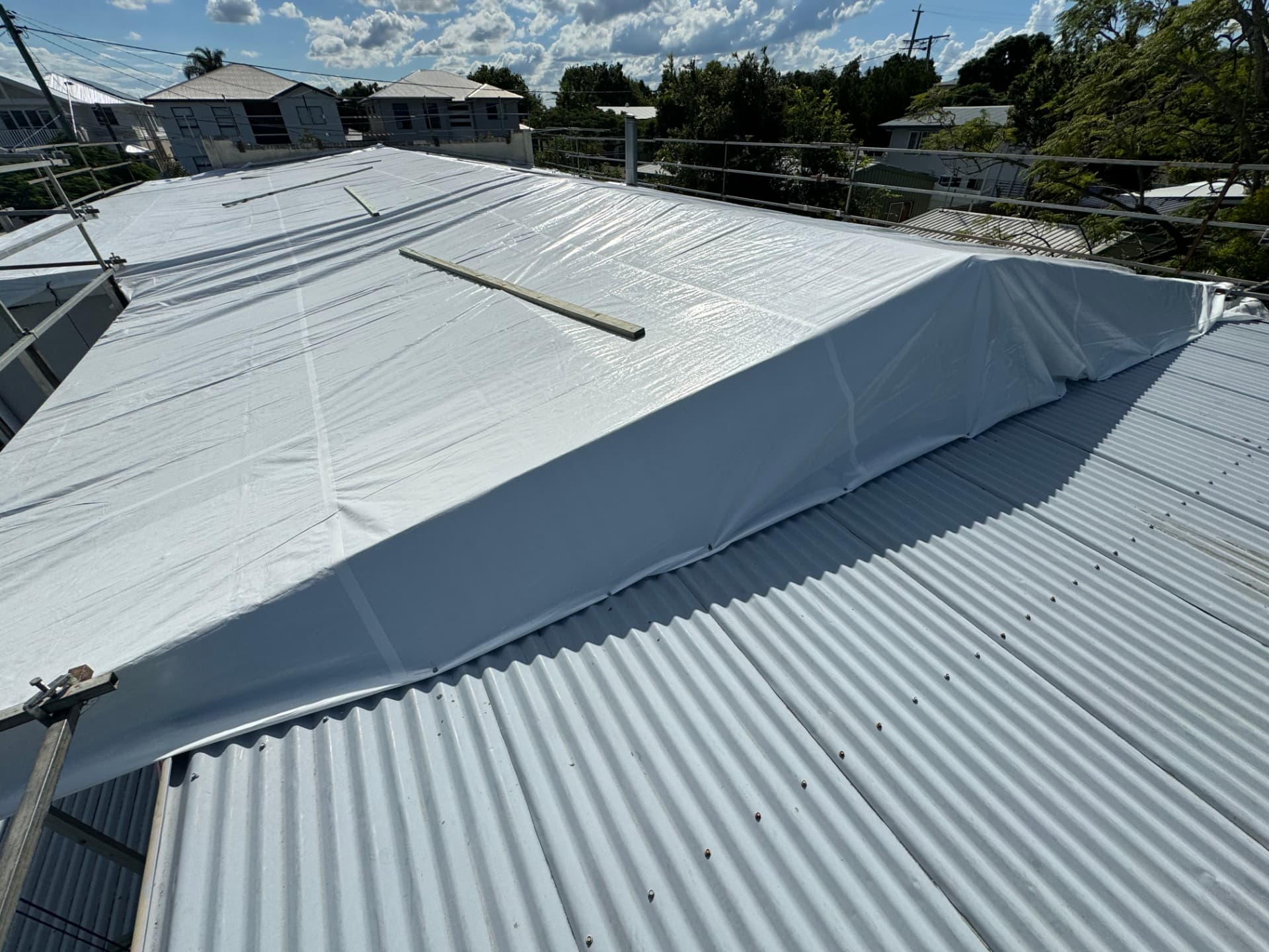 Completed white temporary roof encapsulation sealed and battened across a corrugated roof