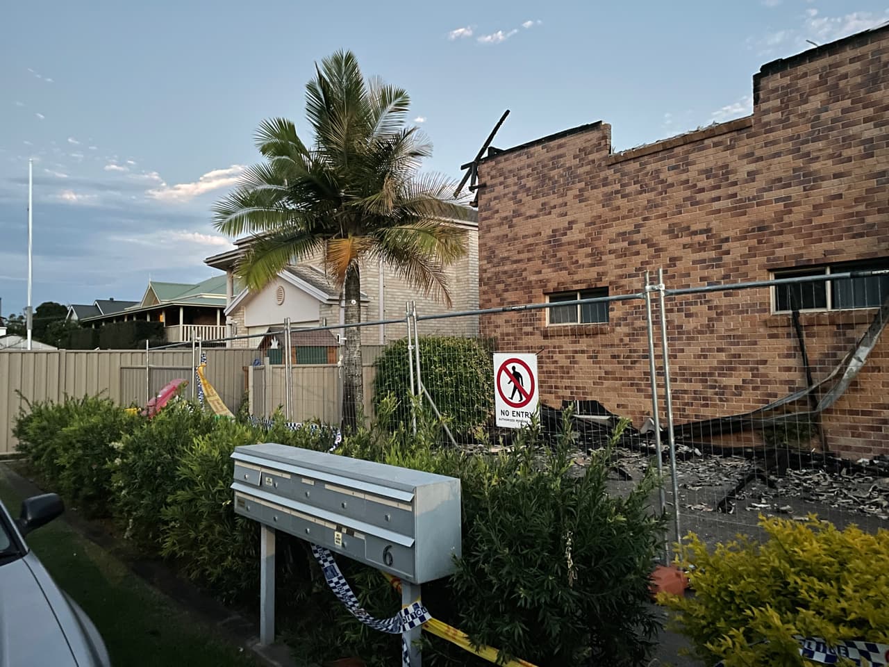 Temporary site fencing panels installed around a fire-damaged brick unit block