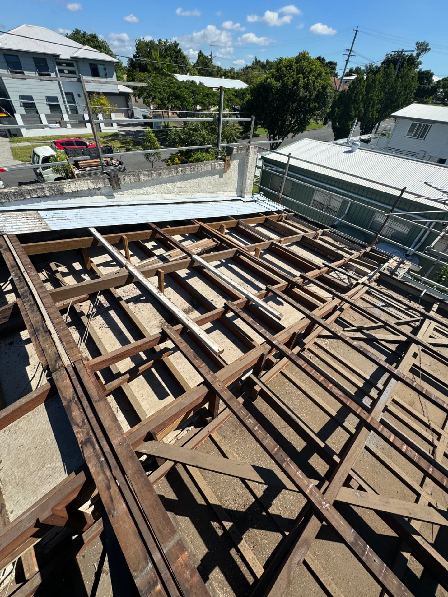 Residential roof stripped to bare rafters and battens with scaffold edge protection in place