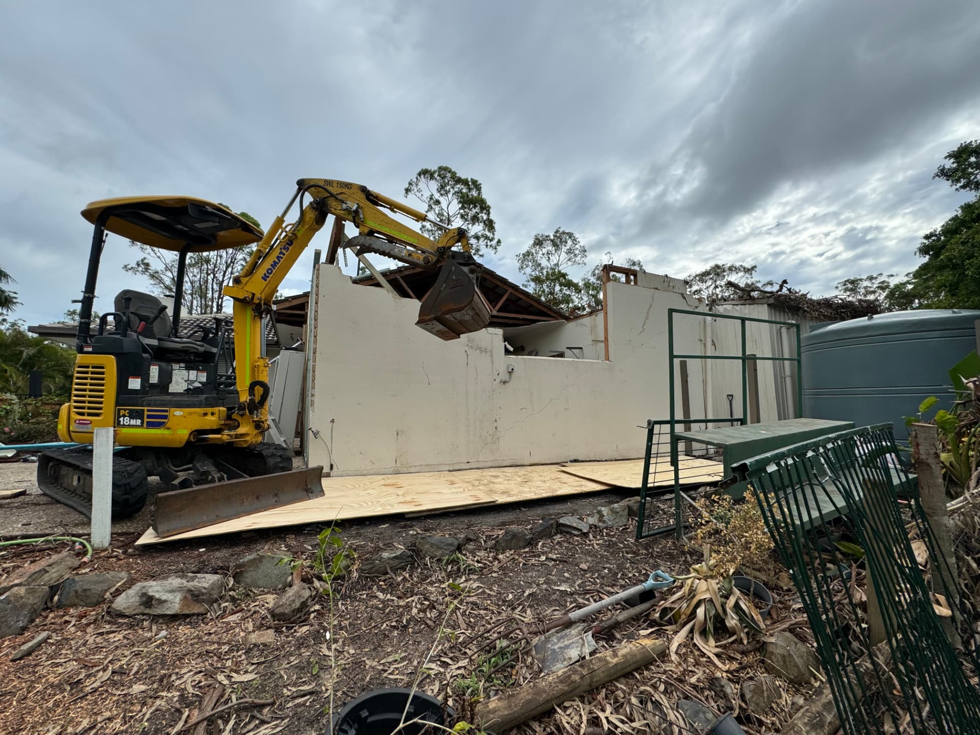 All Makesafes excavator demolishing the damaged section of a storm-hit building under grey skies