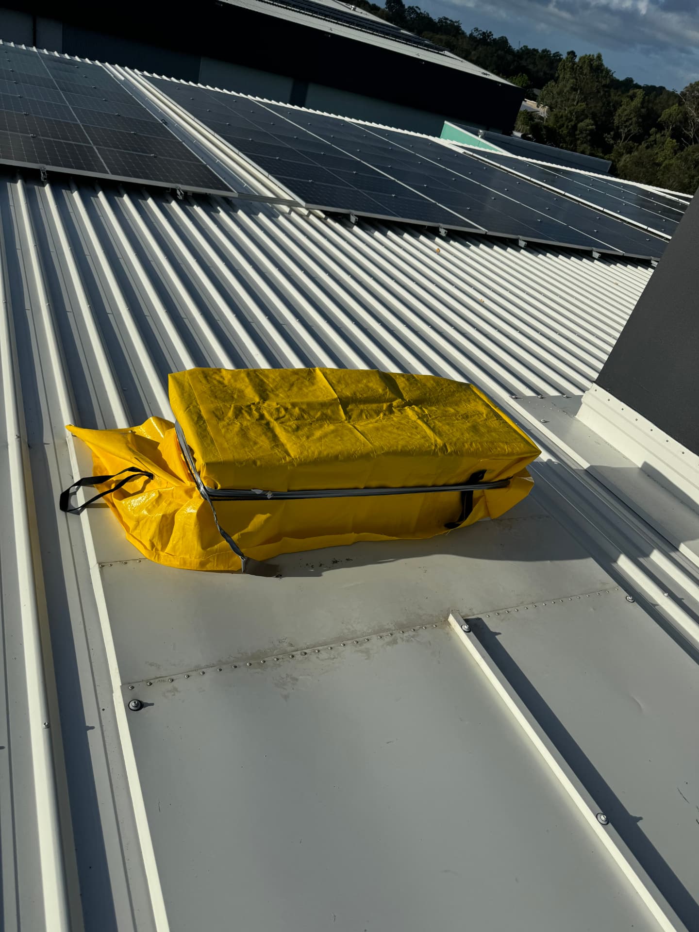 Folded heavy-duty tarp staged on a commercial metal roof beside a solar array