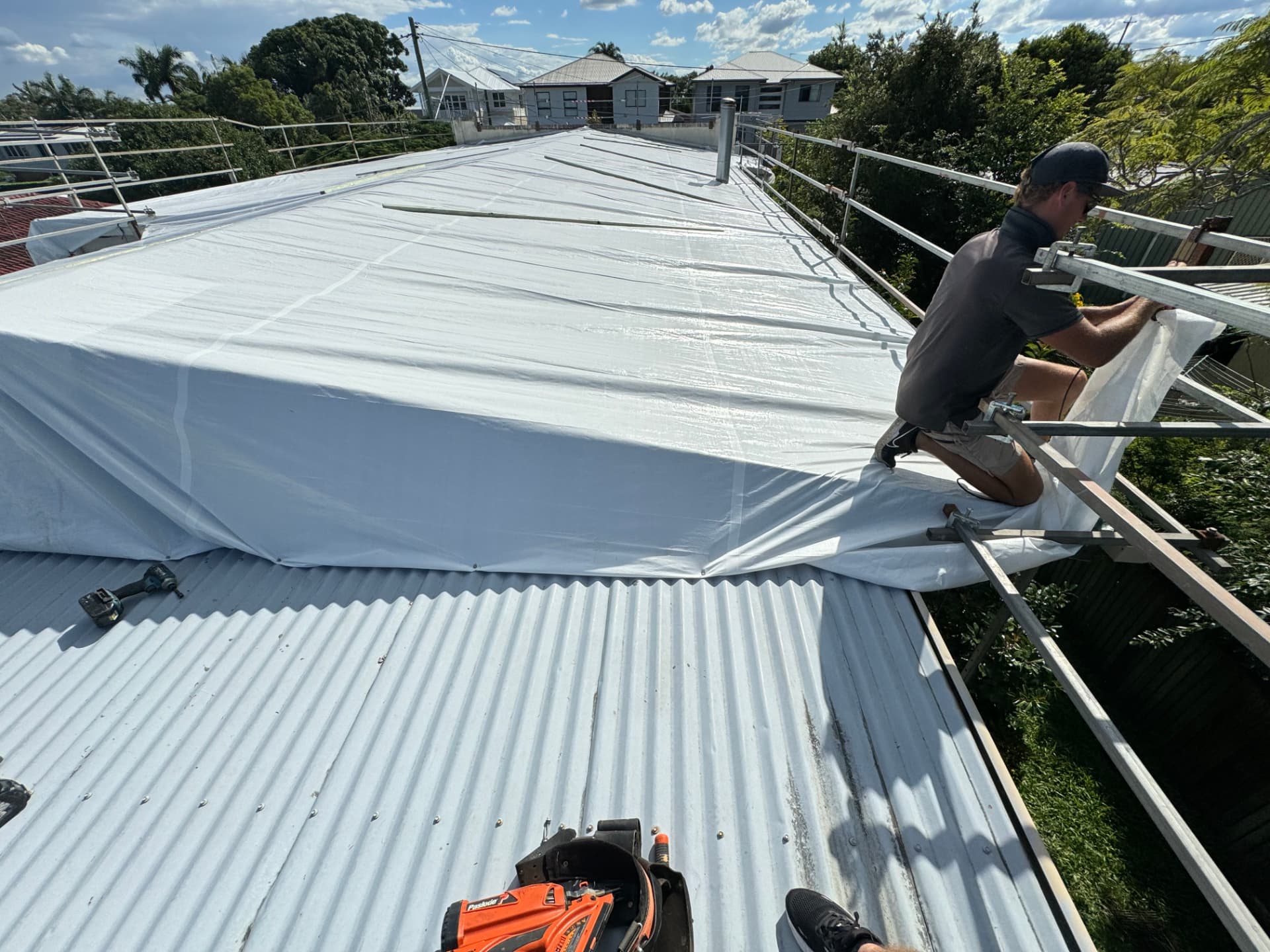 All Makesafes team member securing white temporary roof encapsulation from the scaffold edge