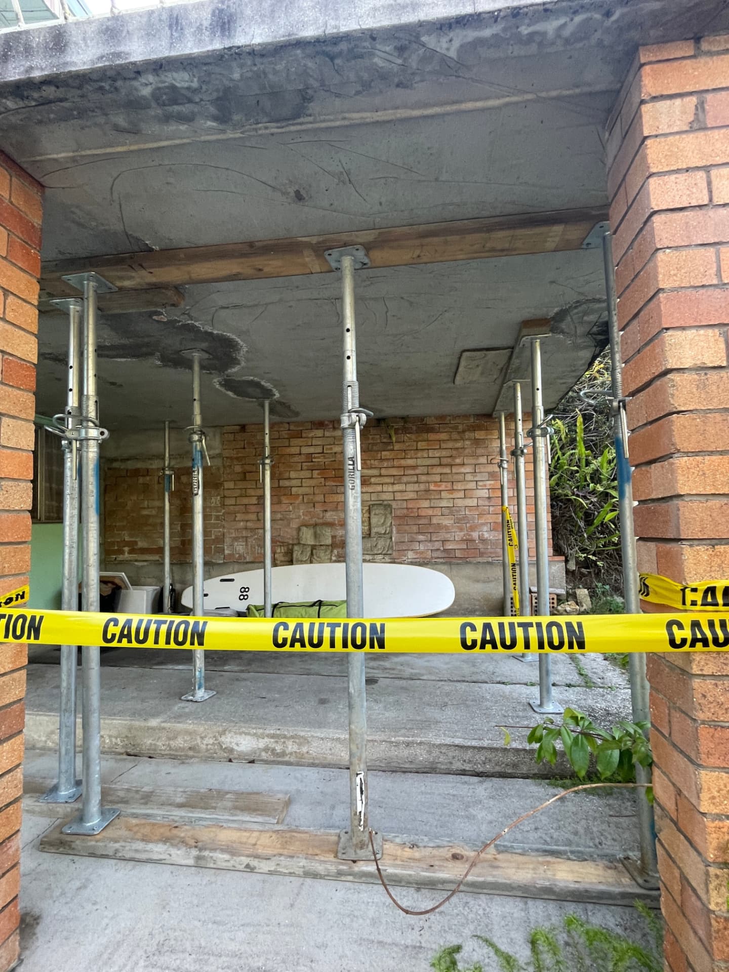 Concrete slab propped with acrow props and closed off with caution tape at a residence