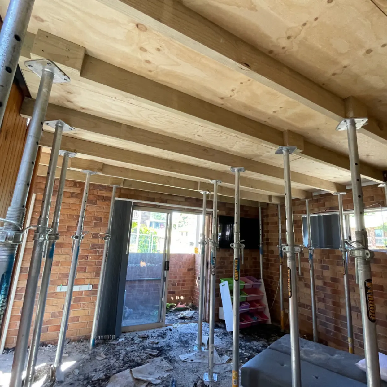 Adjustable acrow props supporting new timber bearers across an opened-up brick residence