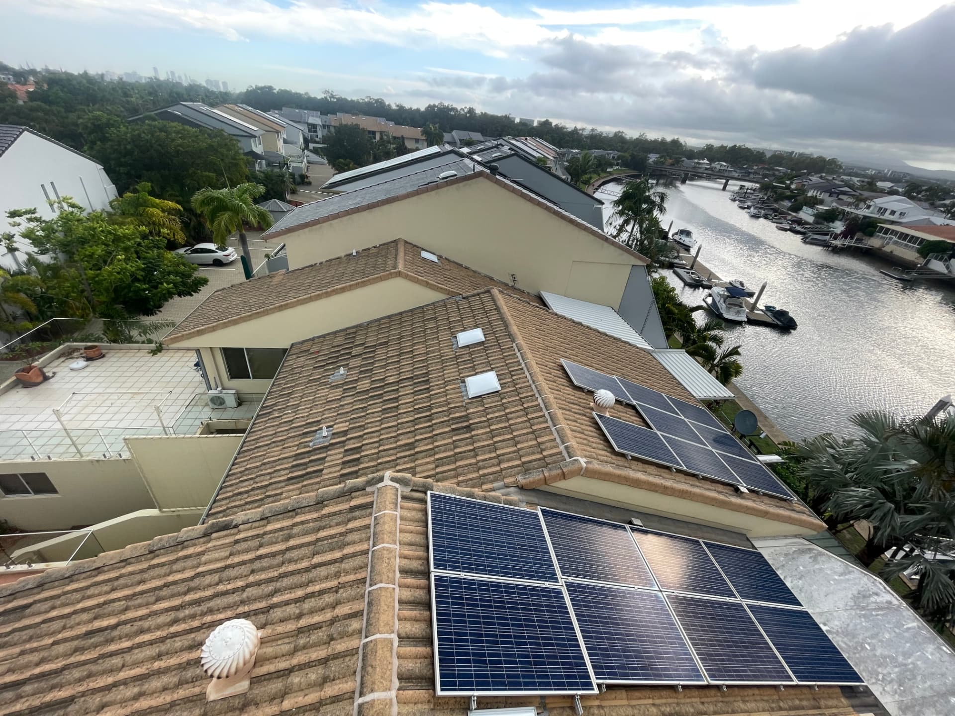 Overview of a large tiled canal-front roof and solar arrays showing the scale and access of the site